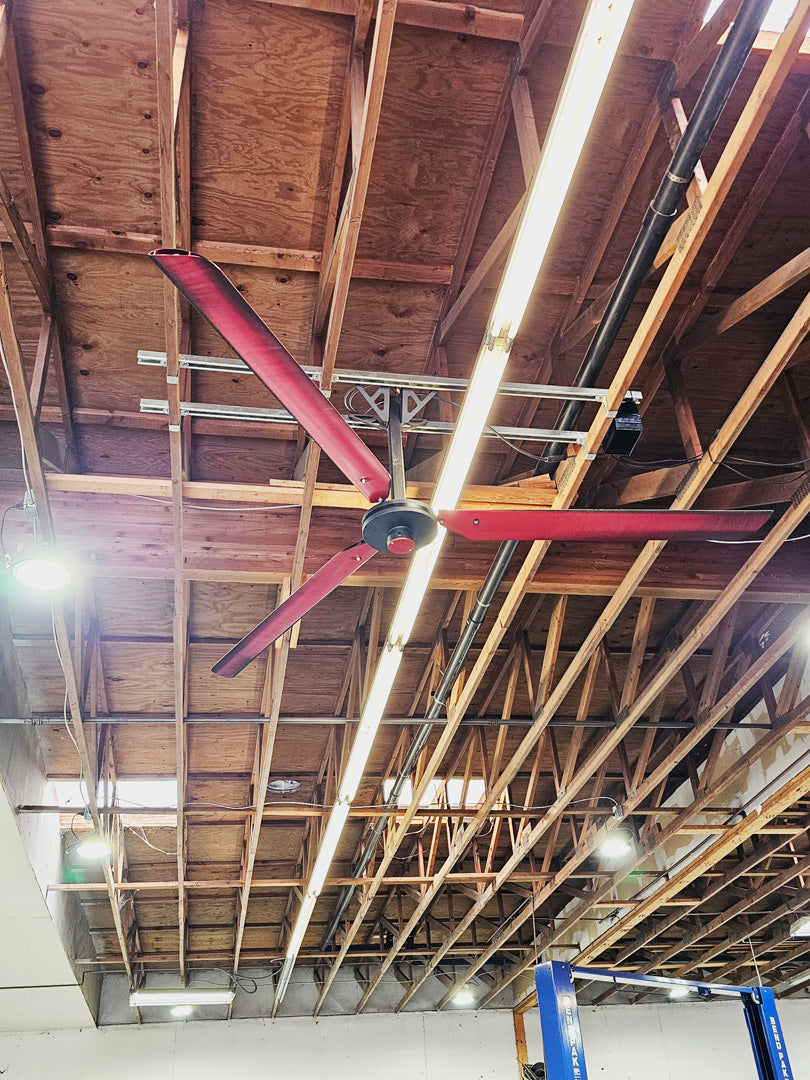 DF3 Red 3 blade Industrial Ceiling Fan, product of Industrial Fan Co, mounted on a wooden beam of a wooden roof, with a long light fixture behind it