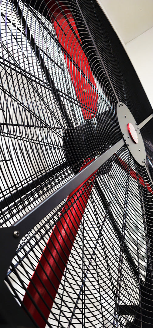 Close up of a metal frame for a 72" Floor Fan with black motor housing, red blades and red and white branded badge, product of Industrial Fan Co