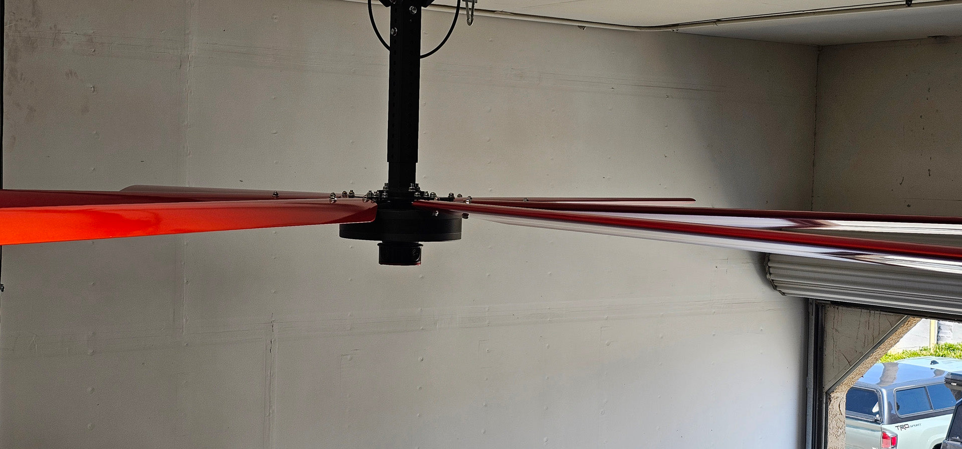 Side view of a telescoping mount, motor, and 6 blades for DF6 Red Industrial Ceiling Fan from Industrial Fan Co, mounted on the ceiling with a gray wall in the background