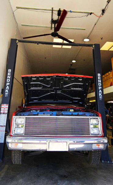 Red car on a lift in a garage and a DF3 Industrial Ceiling Fan above it, product of Industrial Fan Co