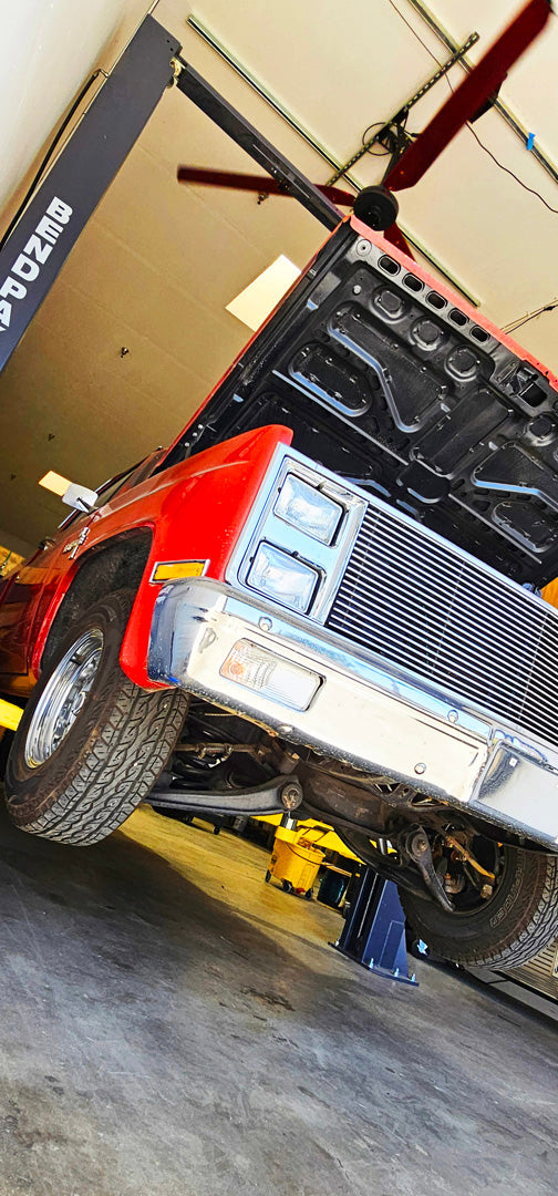 Red car on a lift in a garage and a DF3 Industrial Ceiling Fan above it, product of Industrial Fan Co