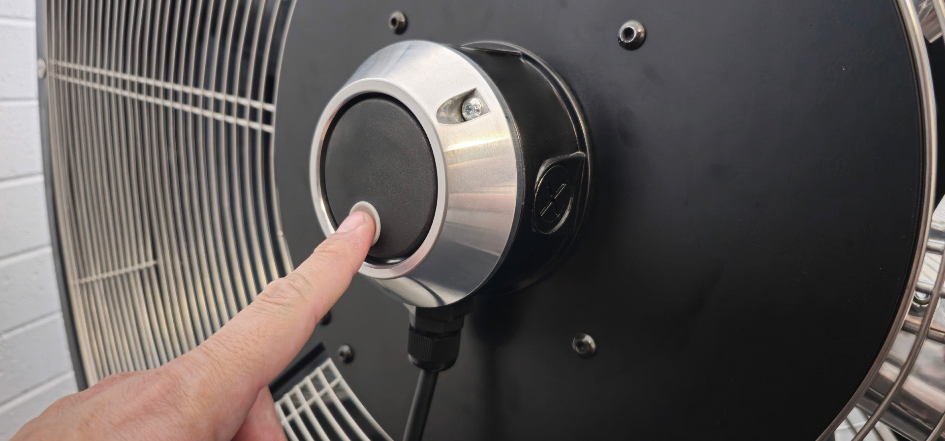Close-up of hand adjusting a black and silver industrial floor fan blade and variable speed controller for 48" Floor Fan, product of Industrial Fan Co