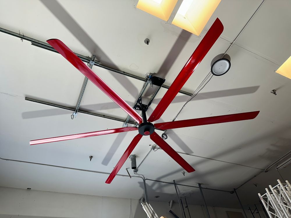 Full size picture of a wall mount, motor casing, red and silver brand badge and 6 blades for DF6 Red Industrial Ceiling Fan, product of Industrial Fan Co, mounted on the ceiling with yellow light fixtures around it