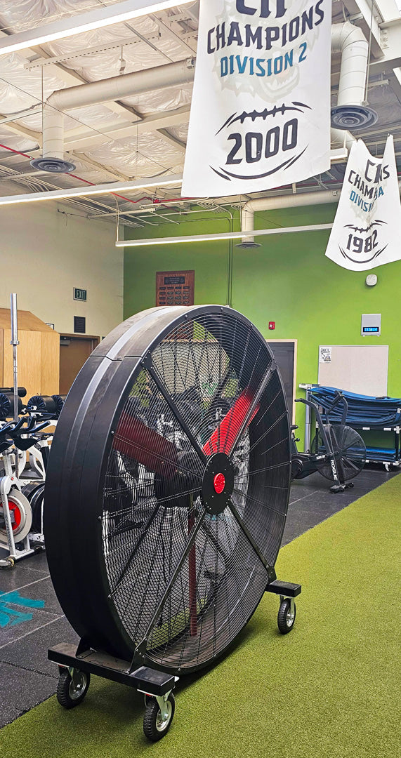 72" Floor Fan with black housing, red blades, metal frame, black and silver casters and metal bearings, product of Industrial Fan Co, in a high-school gym setting