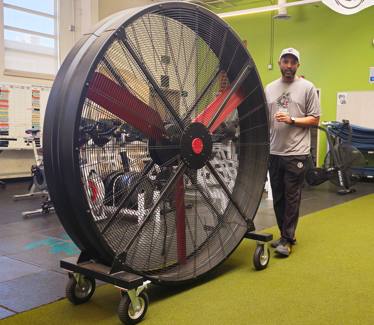 72" Floor Fan with black housing, red blades, metal frame, black and silver casters and metal bearings, product of Industrial Fan Co, in a high-school gym setting