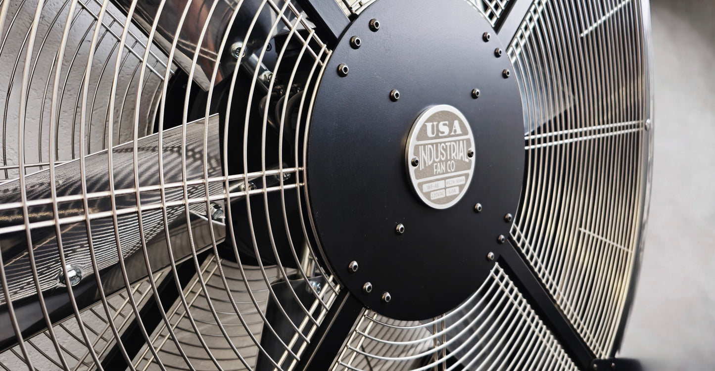 Close-up of a 48" industrial floor fan with silver blades and black housing on a white background with a visible brand logo, product of Industrial Fan Co large 