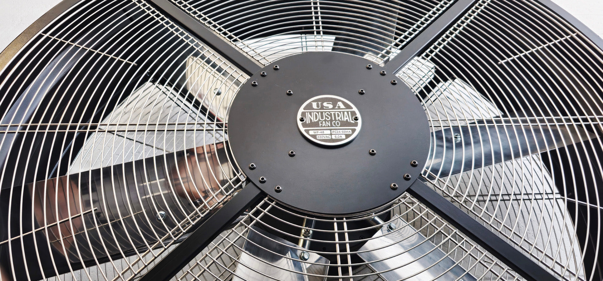 Close-up of a 48" industrial floor fan with silver blades and black housing on a white background with a visible brand logo, product of Industrial Fan Co large 