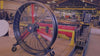 WF72 Industrial Floor Fan, product of Industrial Fan Co,  72" tall with black housing, red blades, metal frames and big casters, in a industrial hangar with workers walking around